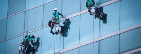 Grupo de trabajadores realizando servicio de limpieza de ventanas.