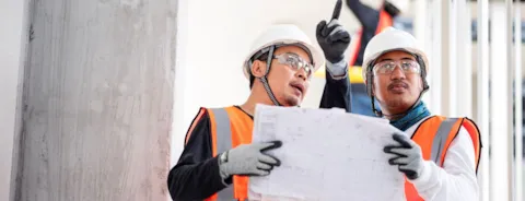 Construction engineers discuss a blueprint or project task details